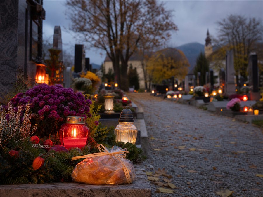 Ruhiger Friedhofsbesuch mit Grablichtern und Blumen rund um Allerheiligen
